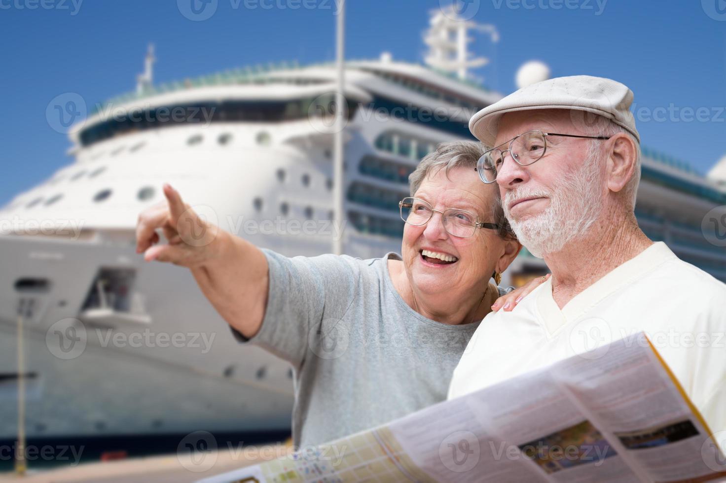 glückliche ältere erwachsene paartouristen mit broschüre neben passagierkreuzfahrtschiff. foto