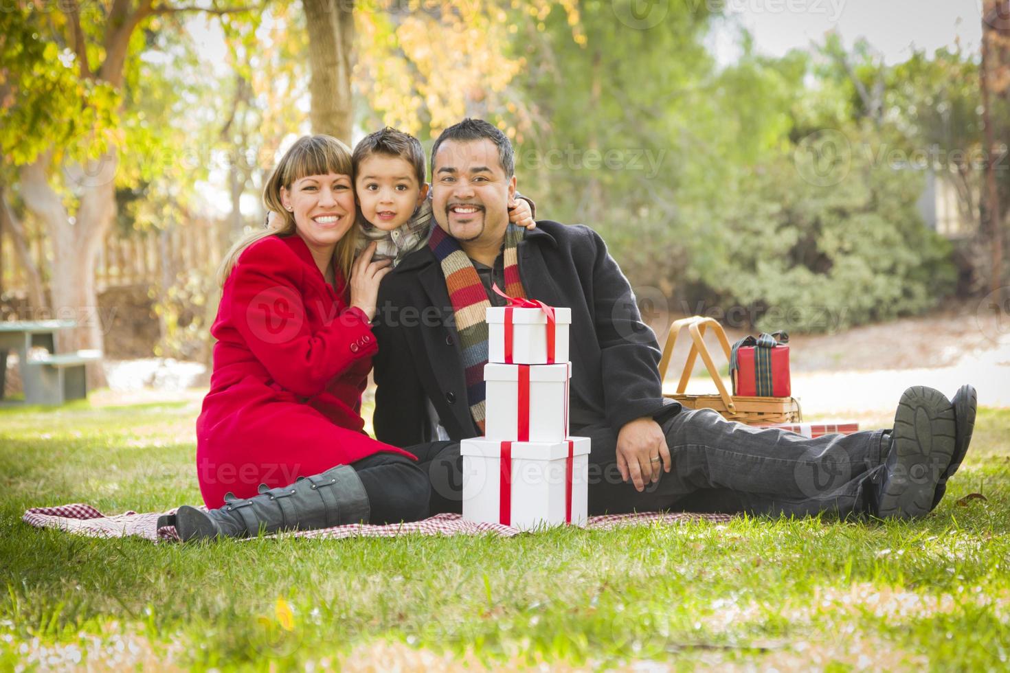 Mischlingsfamilie, die gemeinsam Weihnachtsgeschenke im Park genießt foto