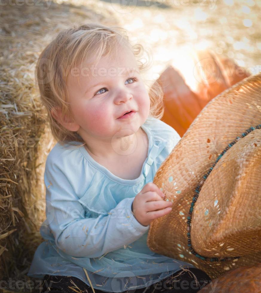 entzückendes Babymädchen mit Cowboyhut am Kürbisbeet foto