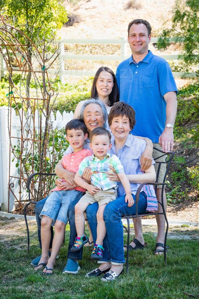 chinesische und kaukasische familie, die auf einer bank sitzt foto