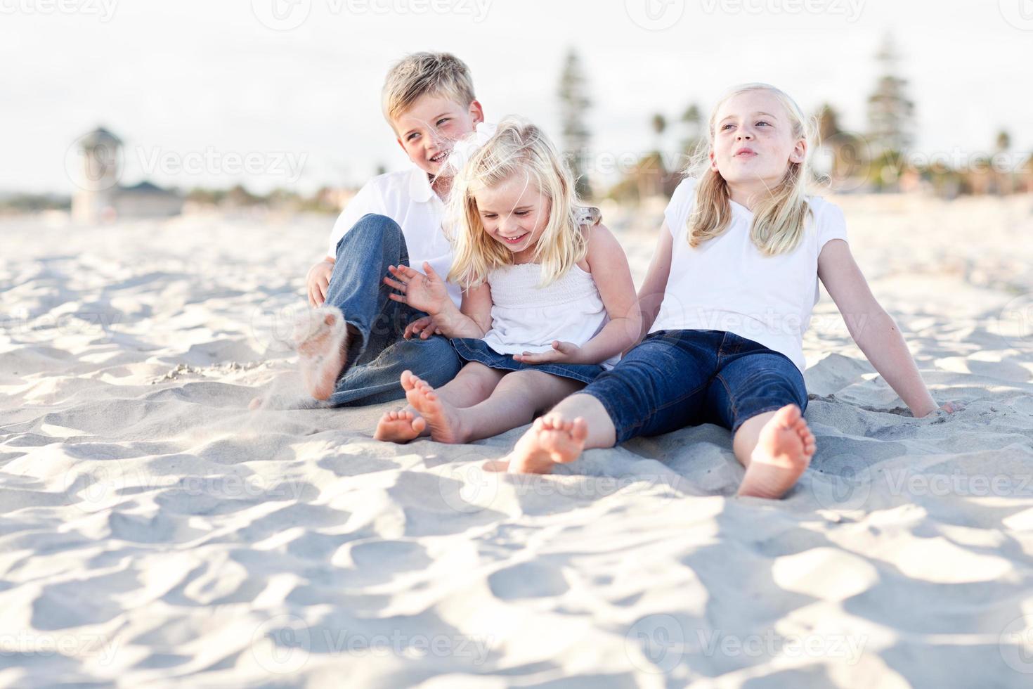 entzückende schwestern und bruder haben spaß am strand foto