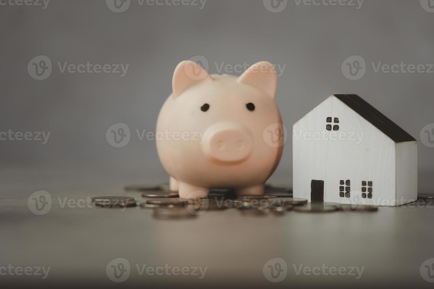finanzen, holzhaus mit einem rosa sparschwein und vielen münzen geld. Sparen Sie Geld und Immobilienkonzept. foto