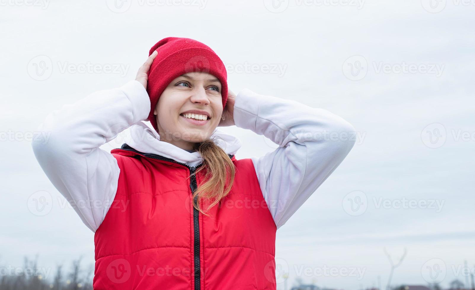 Porträt einer jungen Frau in leuchtend roter und weißer Sportkleidung im Freien foto