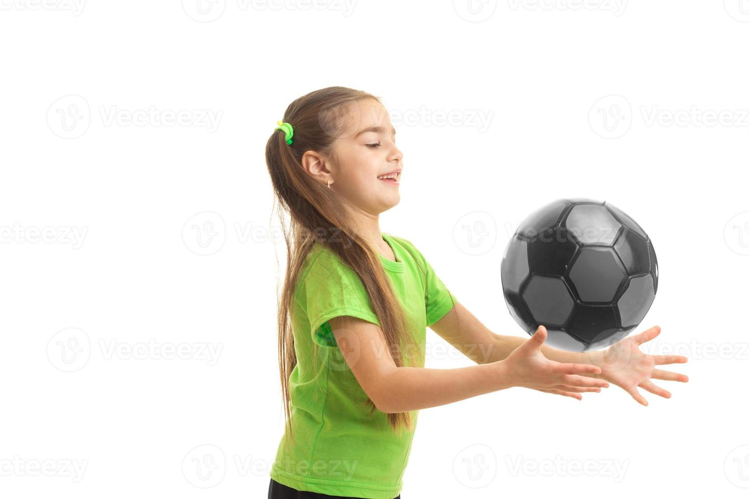 kleines Mädchen im grünen Hemd, das Fußball spielt foto