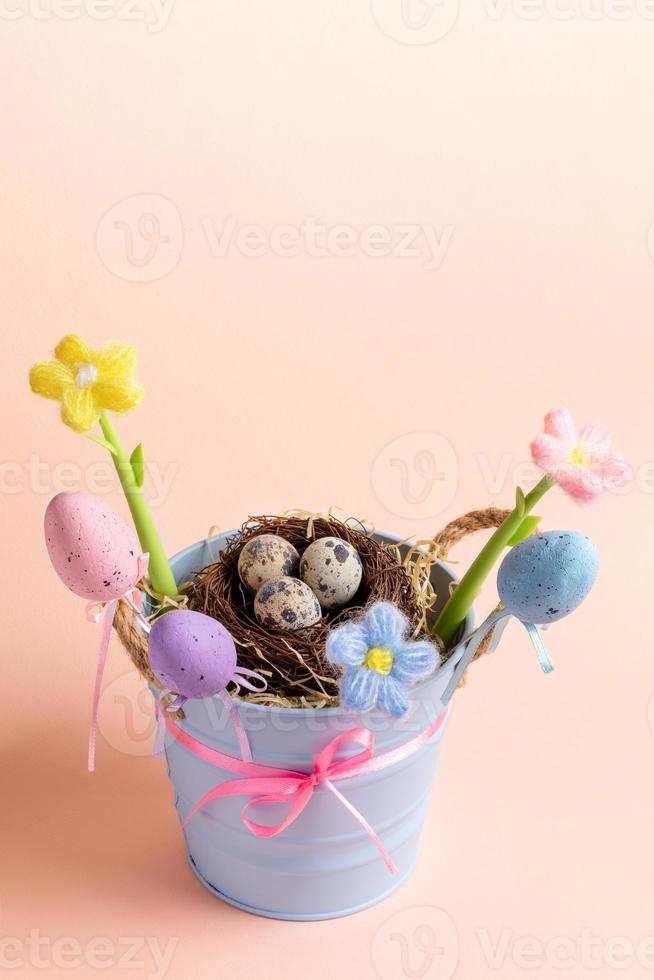 osterkarte - eimer mit nest aus wachteleiern, dekorative eier, gestrickte blumen auf rosa. Platz kopieren. foto