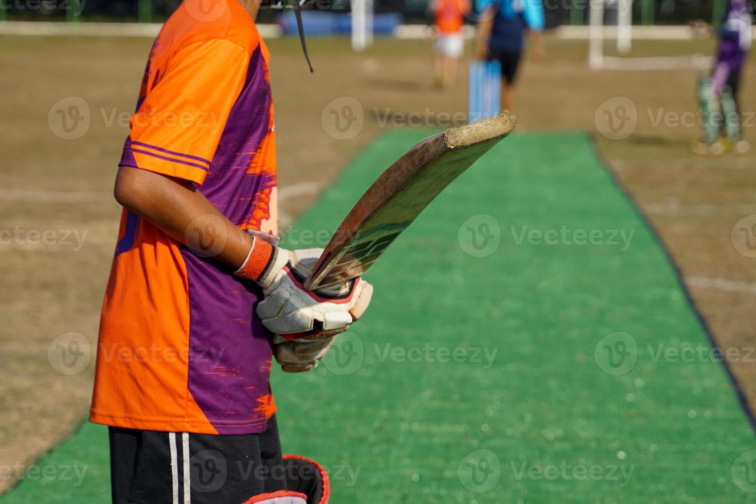 ein Cricketspieler hält den Schläger, während er auf den Cricketball wartet. beim Üben auf dem Feld. weicher und selektiver Fokus. foto