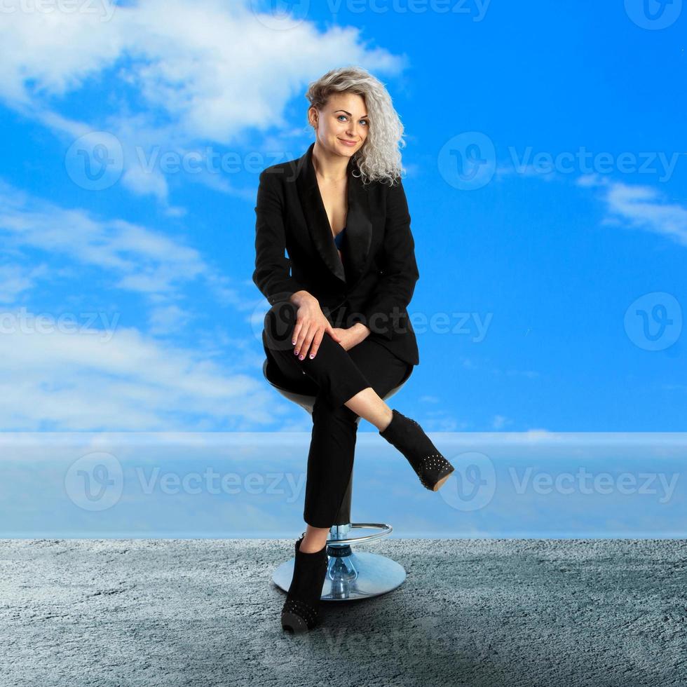 fröhliche blonde Geschäftsfrau sitzt auf Stuhl foto