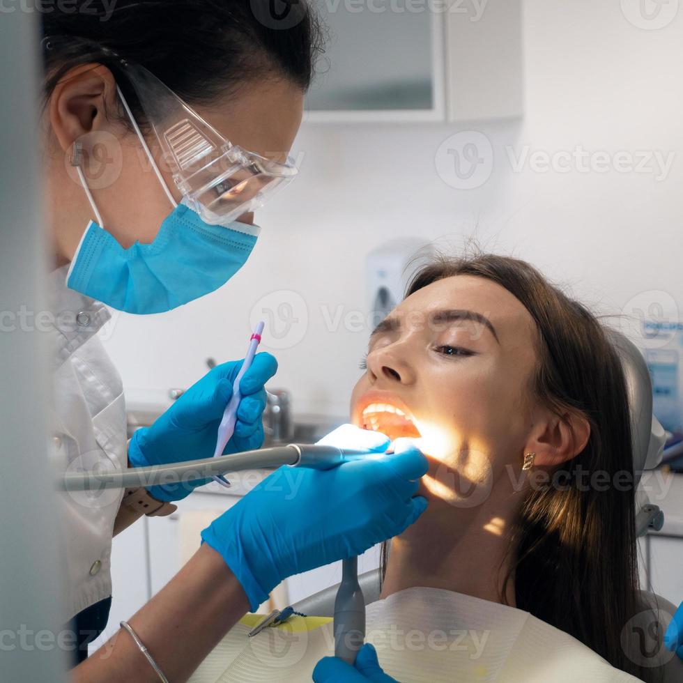 zahnarzt behandelt die zähne eines schönen patienten foto