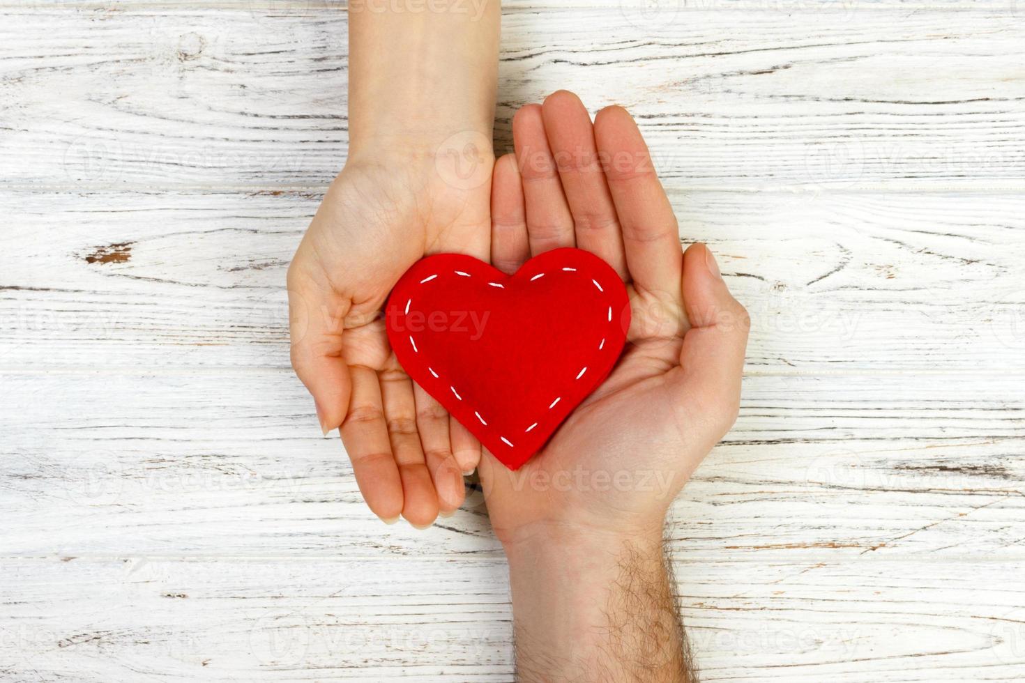 Mann, der einer Frau zärtlich ein weißes Herz anbietet. Valentinstag-Konzept auf einem hölzernen Hintergrund, Ansicht von oben foto