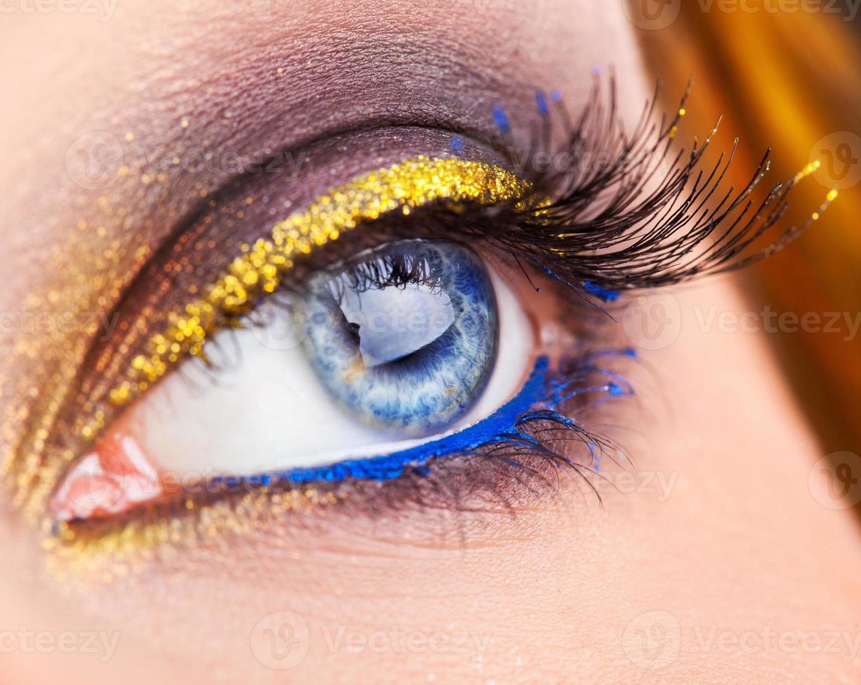 Makrofoto des blauen Auges, das wegschaut. Professionelles Augen-Make-up mit blauen und goldenen Farben. Studioaufnahme foto