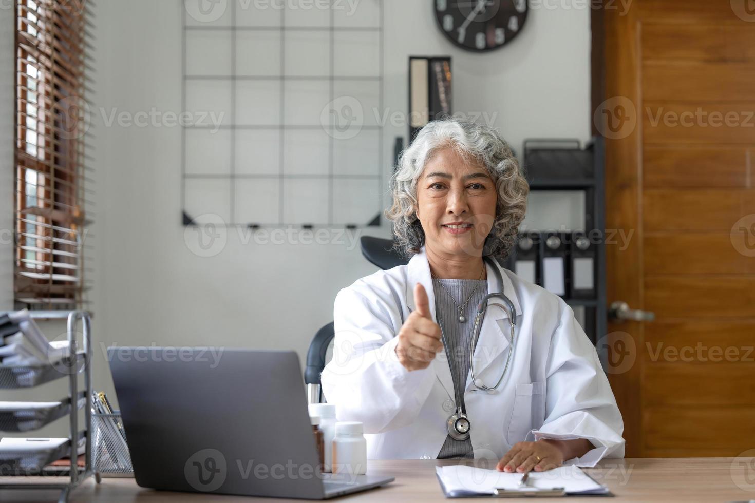 Porträt einer asiatischen Ärztin, die an ihrem Tisch in der Klinik arbeitet foto