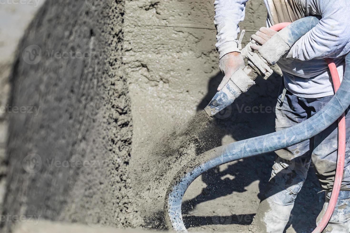 Poolbauer, der Beton, Spritzbeton oder Spritzbeton durch einen Schlauch schießt foto