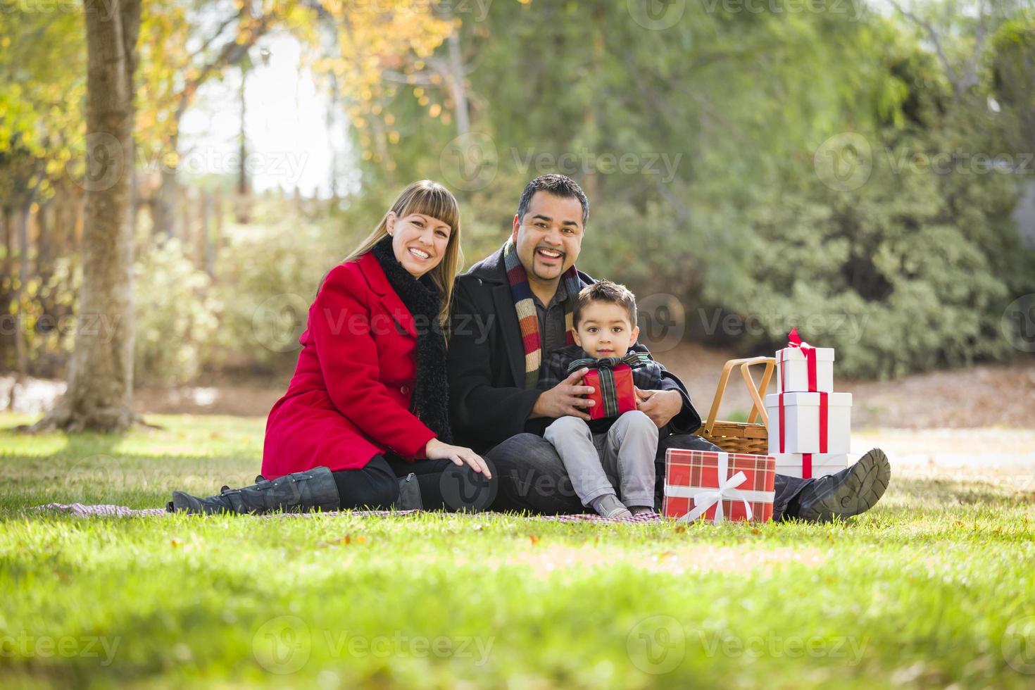 Mischlingsfamilie, die gemeinsam Weihnachtsgeschenke im Park genießt foto