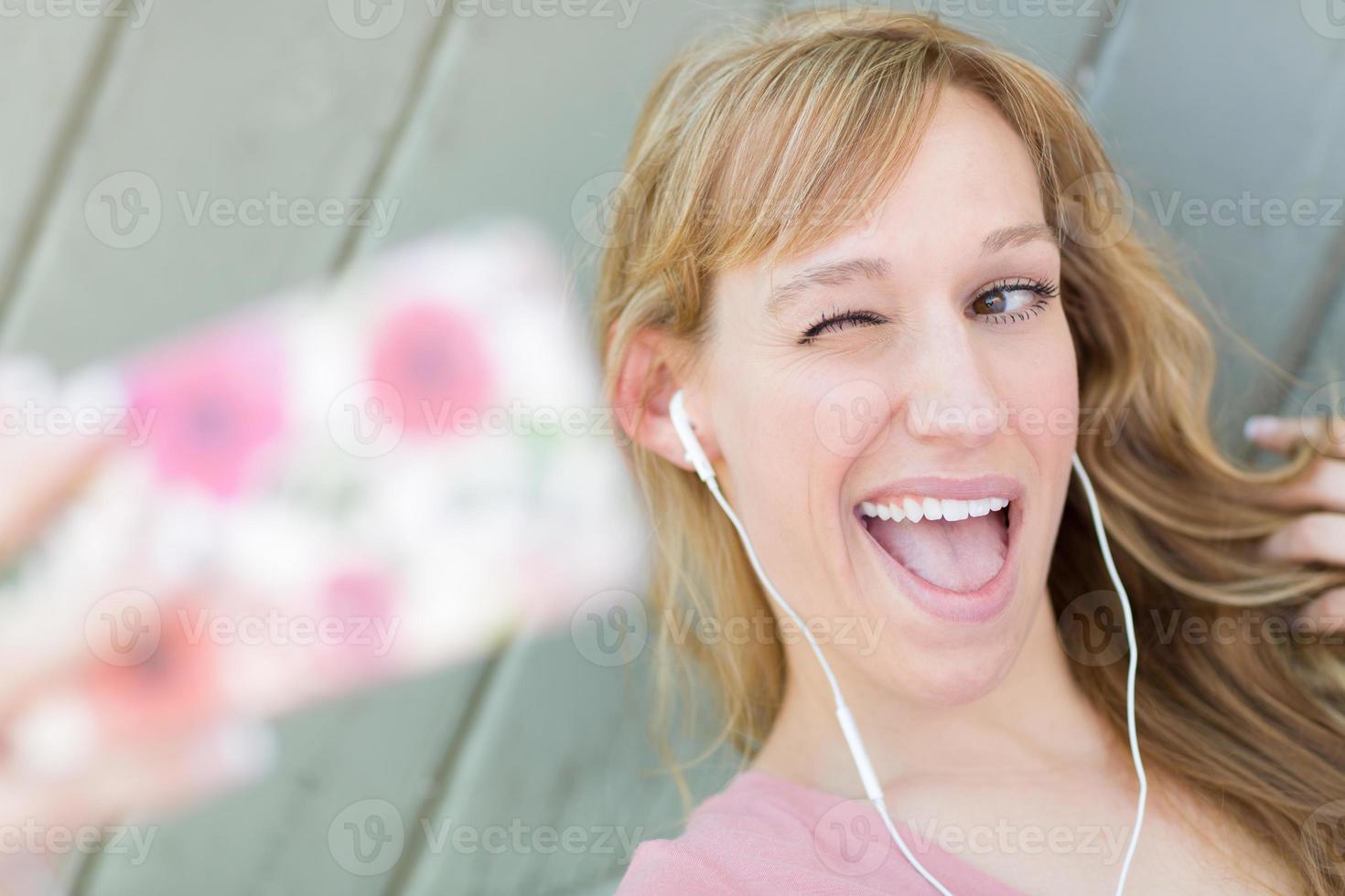 Junge erwachsene Frau mit Kopfhörern, die ein Selfie mit ihrem Smartphone macht. foto