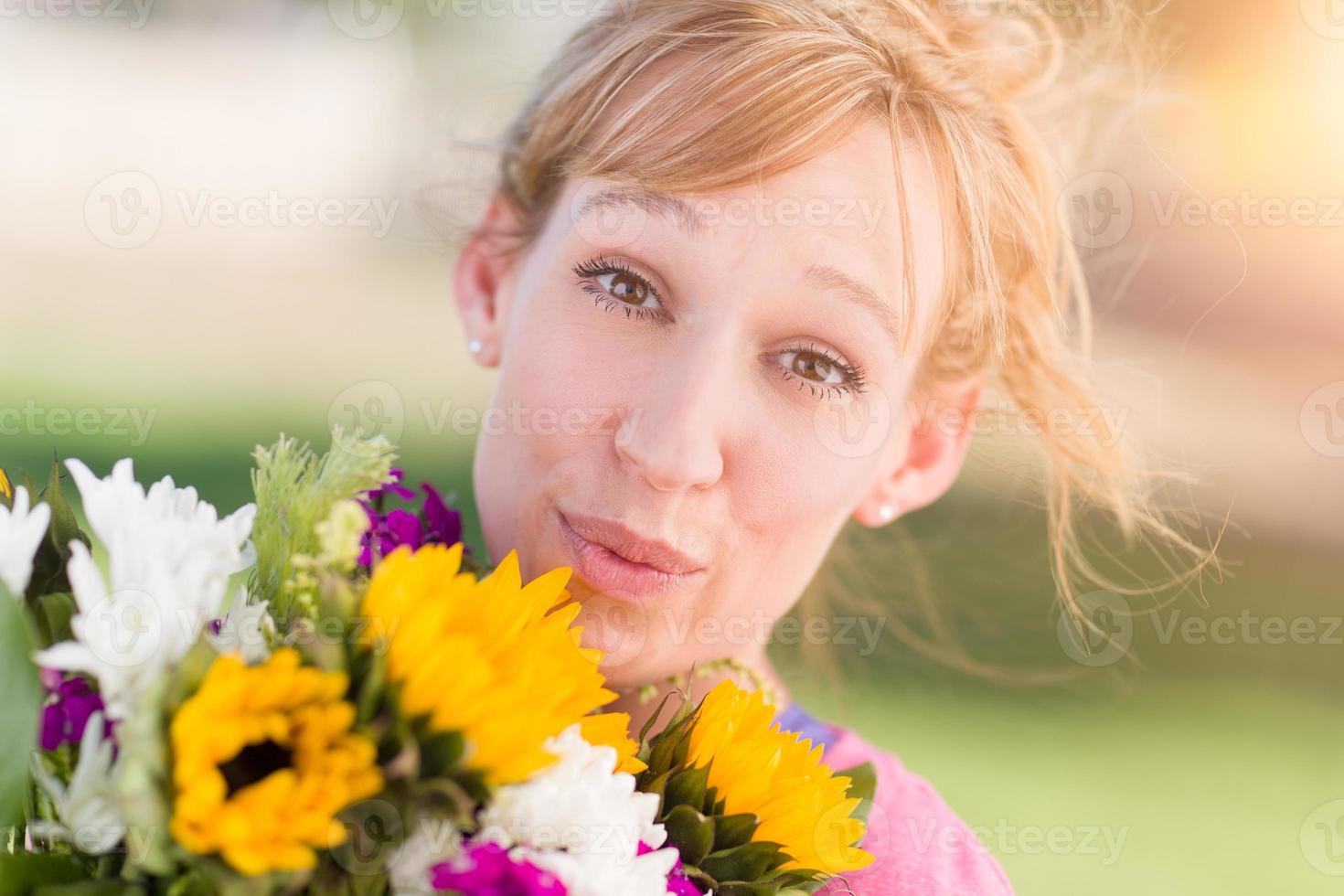 Außenporträt einer aufgeregten jungen erwachsenen Frau mit braunen Augen, die einen Blumenstrauß hält. foto