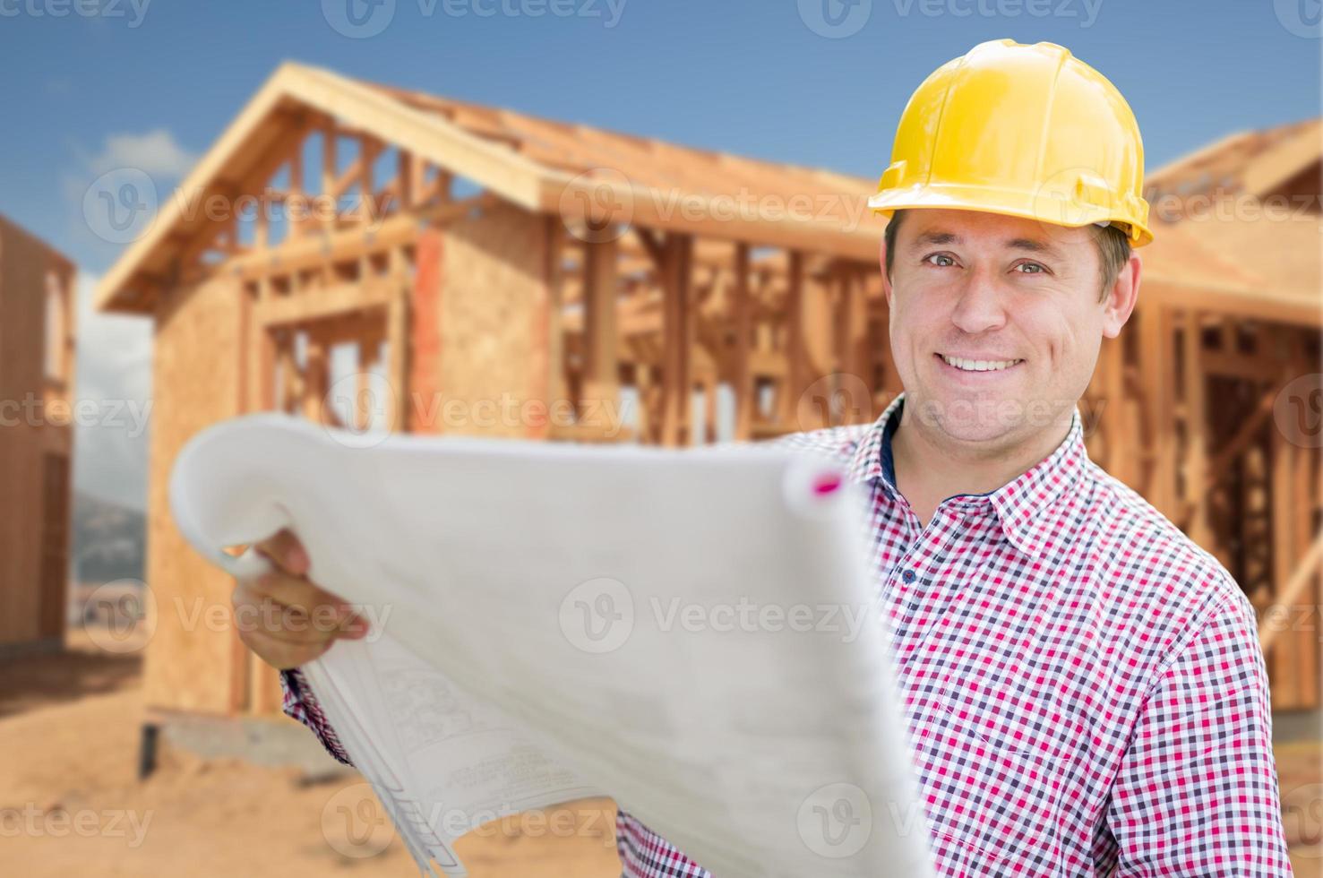 auftragnehmer mit helm, der baupläne auf der baustelle zu hause hält foto