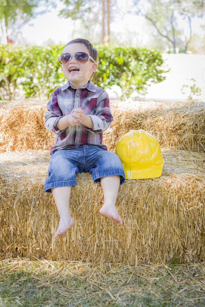 junger Mischlingsjunge, der mit Sonnenbrille und Schutzhelm lacht foto