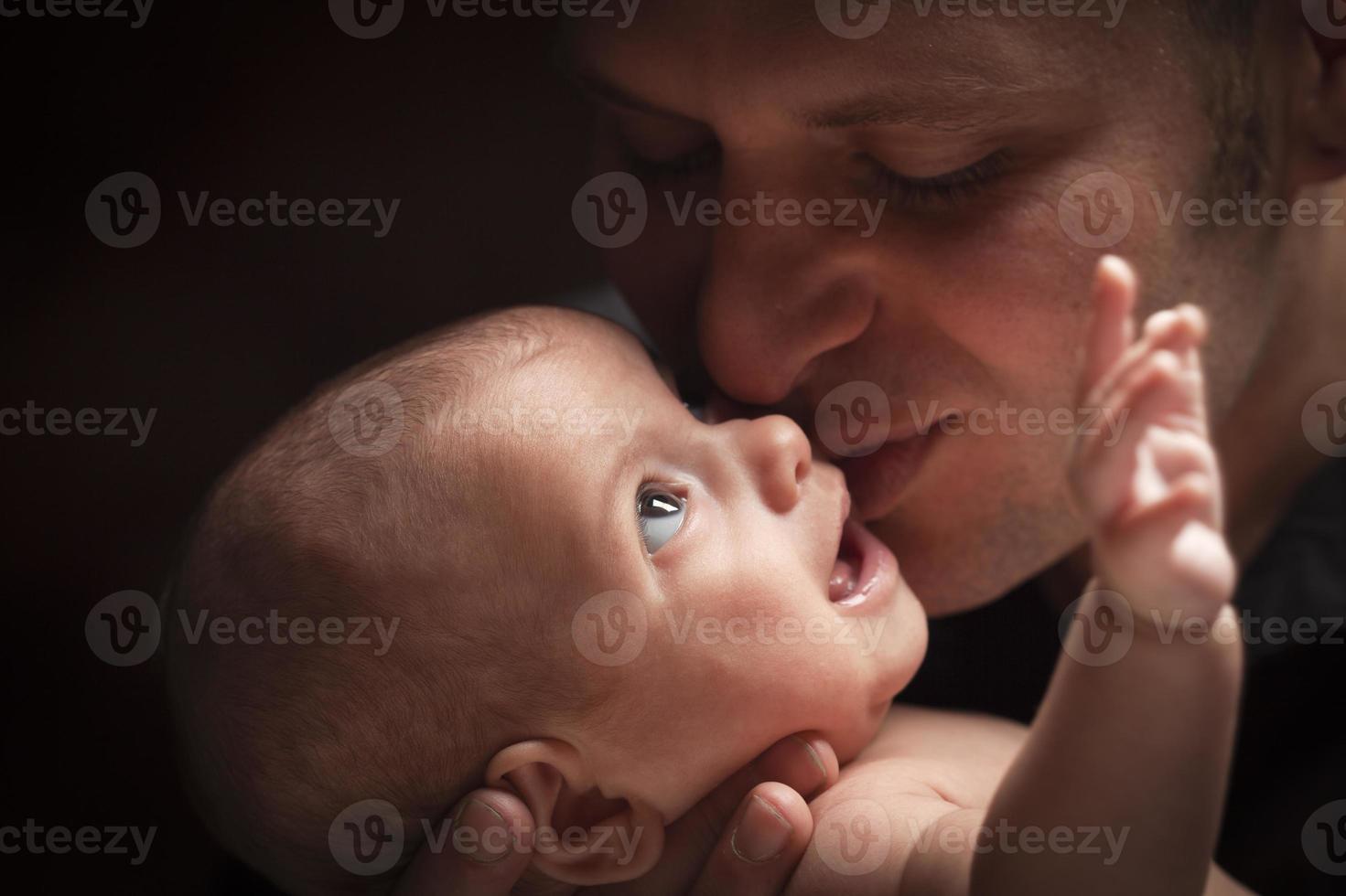 Junger Vater, der sein neugeborenes Baby der gemischten Rasse hält foto