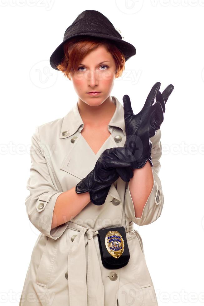 Rothaarige Detektivin zieht Handschuhe an und trägt einen Trenchcoat foto