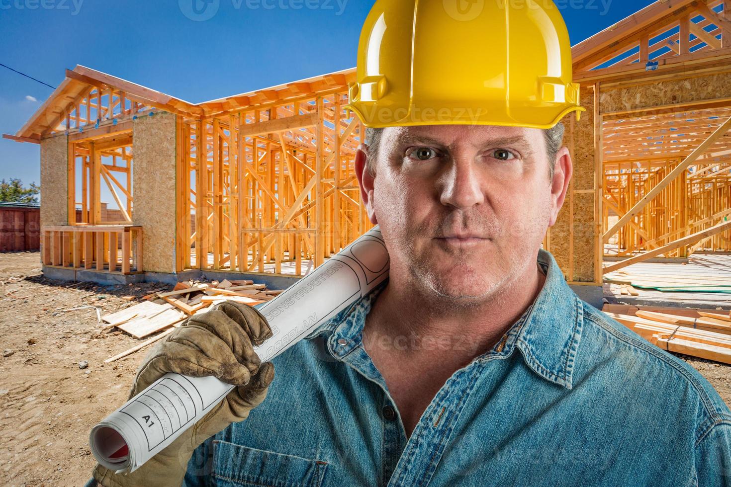 seriöser auftragnehmer mit schutzhelm, der grundrisse auf der baustelle hält. foto