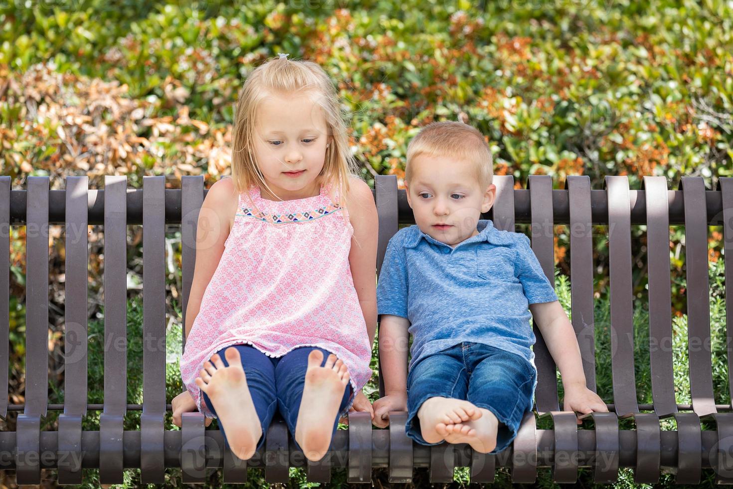 junge schwester und bruder haben spaß auf der bank im park foto