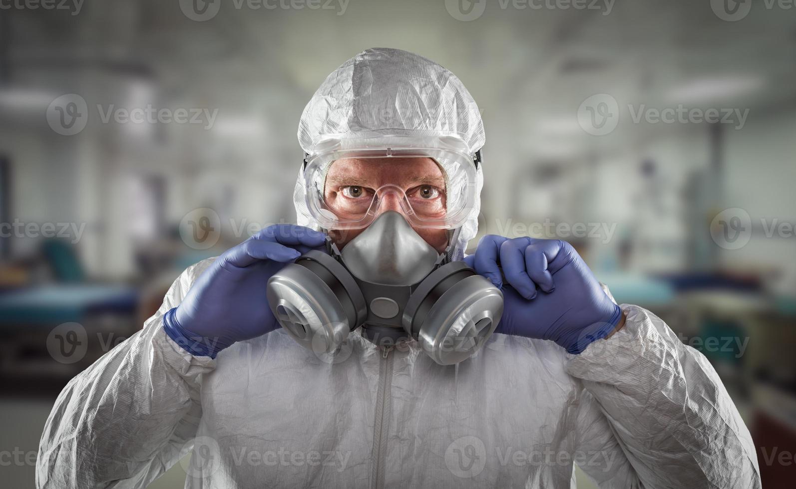 Mann mit Hazmat-Anzug, Schutzgasmaske und Schutzbrille im Krankenhaus. foto
