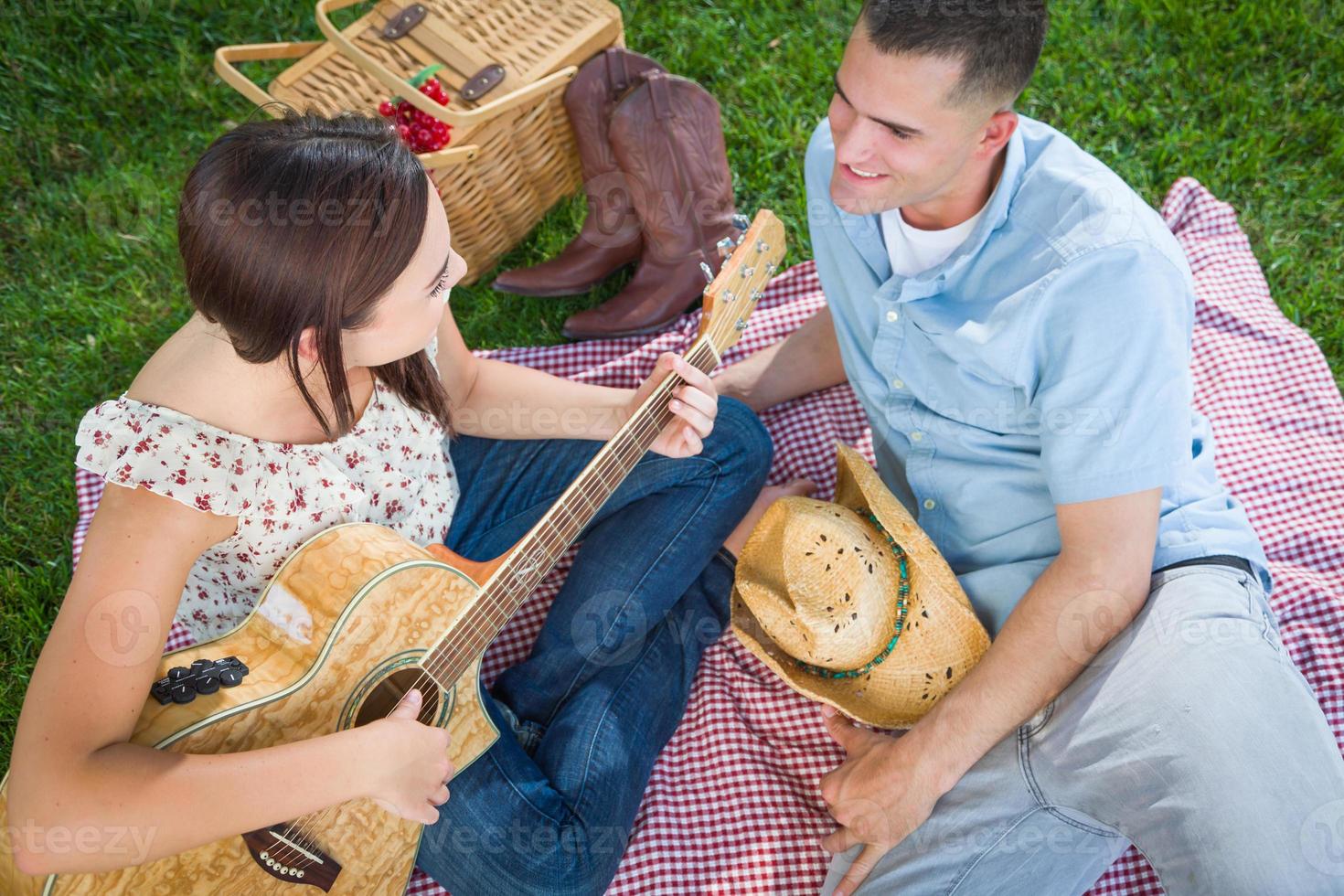 junges erwachsenes mädchen, das mit freund im park gitarre spielt. foto