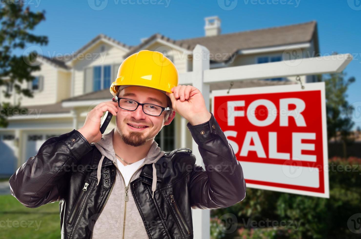 Bauunternehmer mit Schutzhelm vor Haus und Schild foto