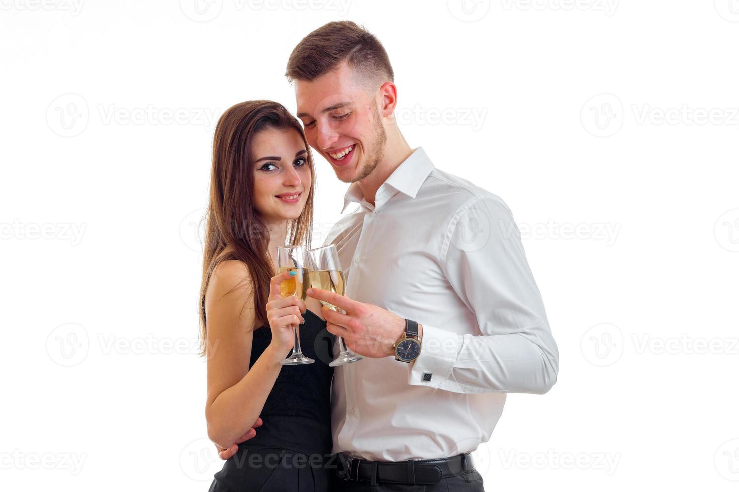 junger liebevoller kerl mit einem mädchen, das in der nähe steht und champagnergläser trägt foto