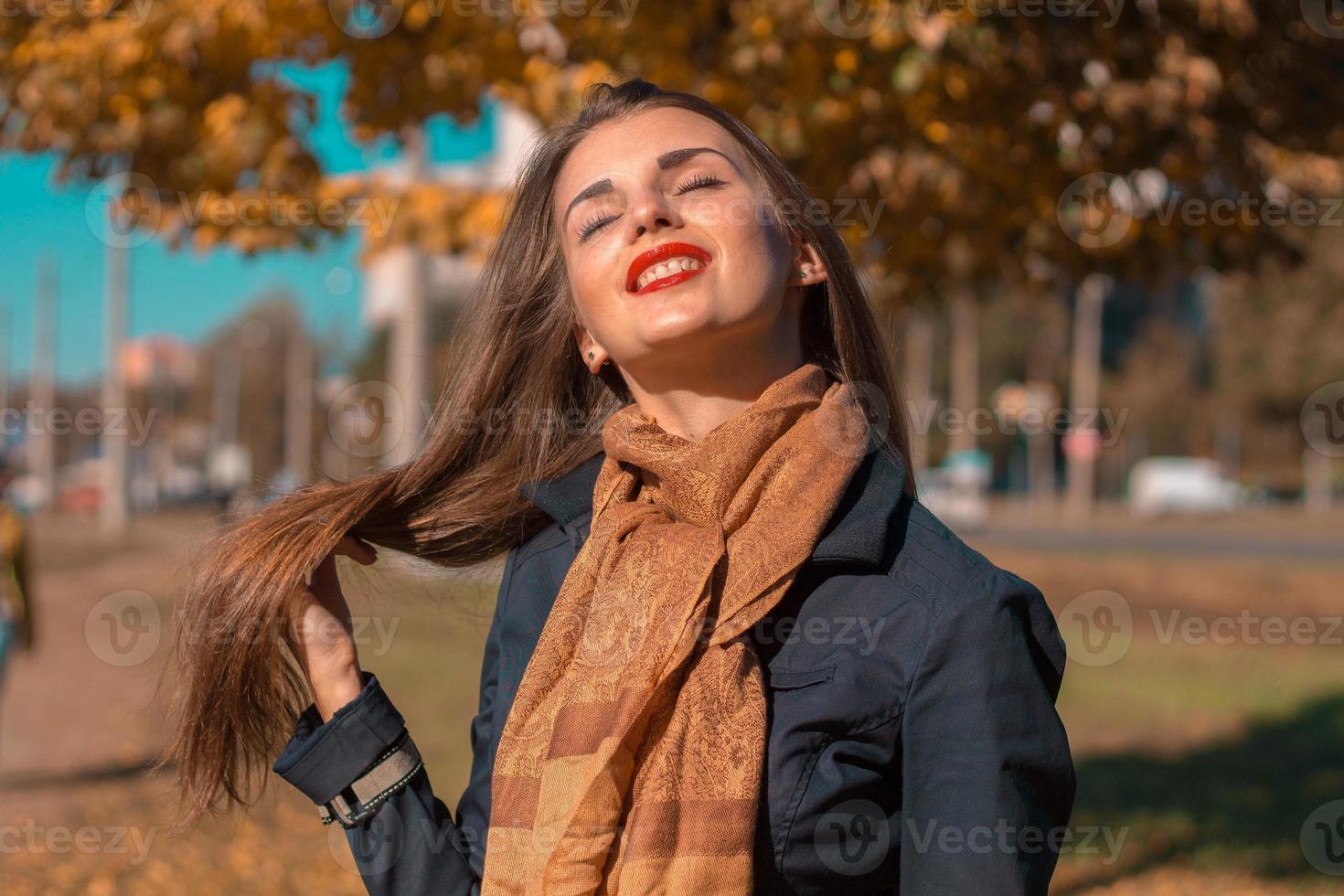 junges mädchen mit schal hält haarhand und hob ihren kopf zur sonne foto