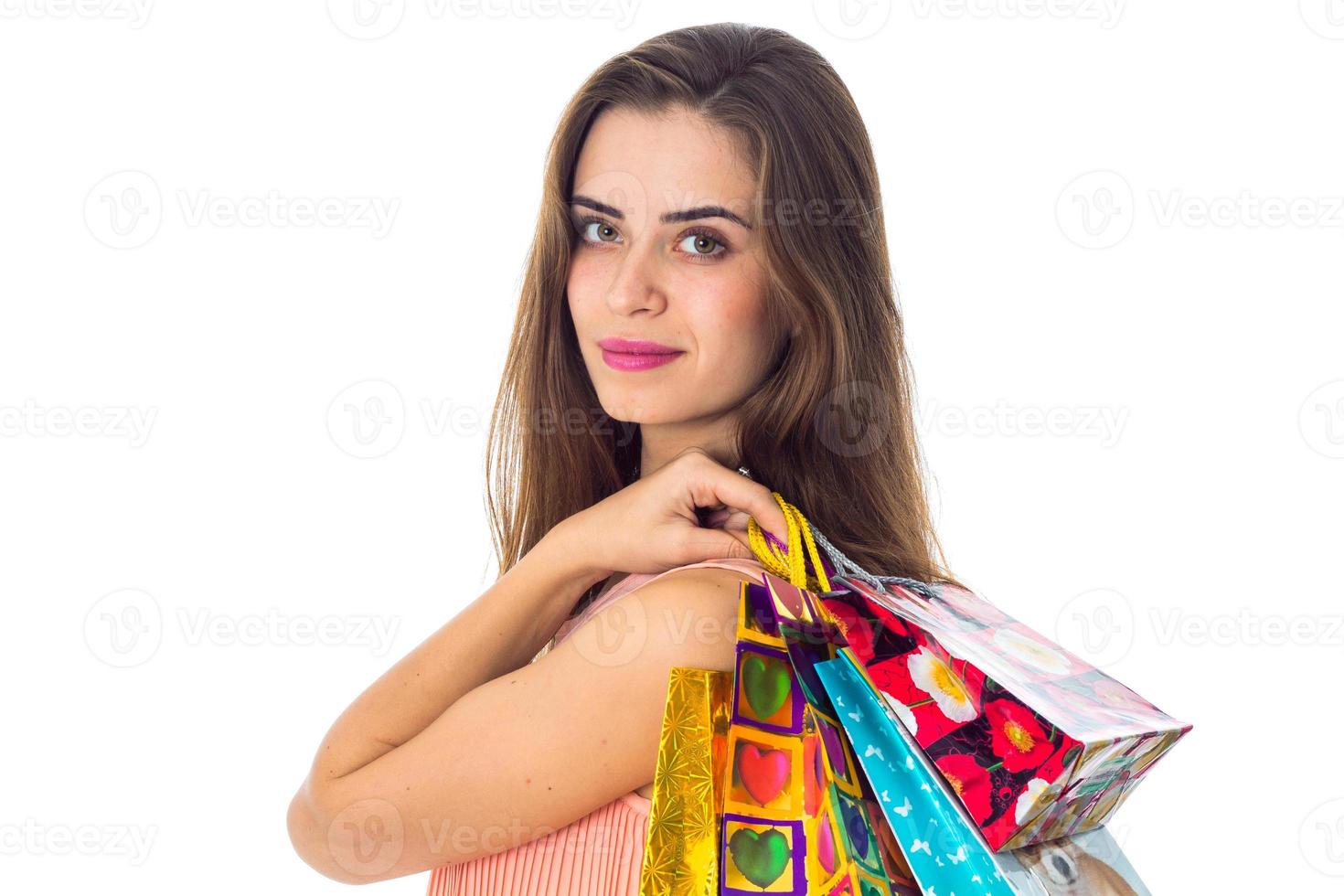 Porträt eines schönen jungen Mädchens, das nach vorne schaut und farbige Taschen in der Hand hält, die auf weißem Hintergrund isoliert sind foto