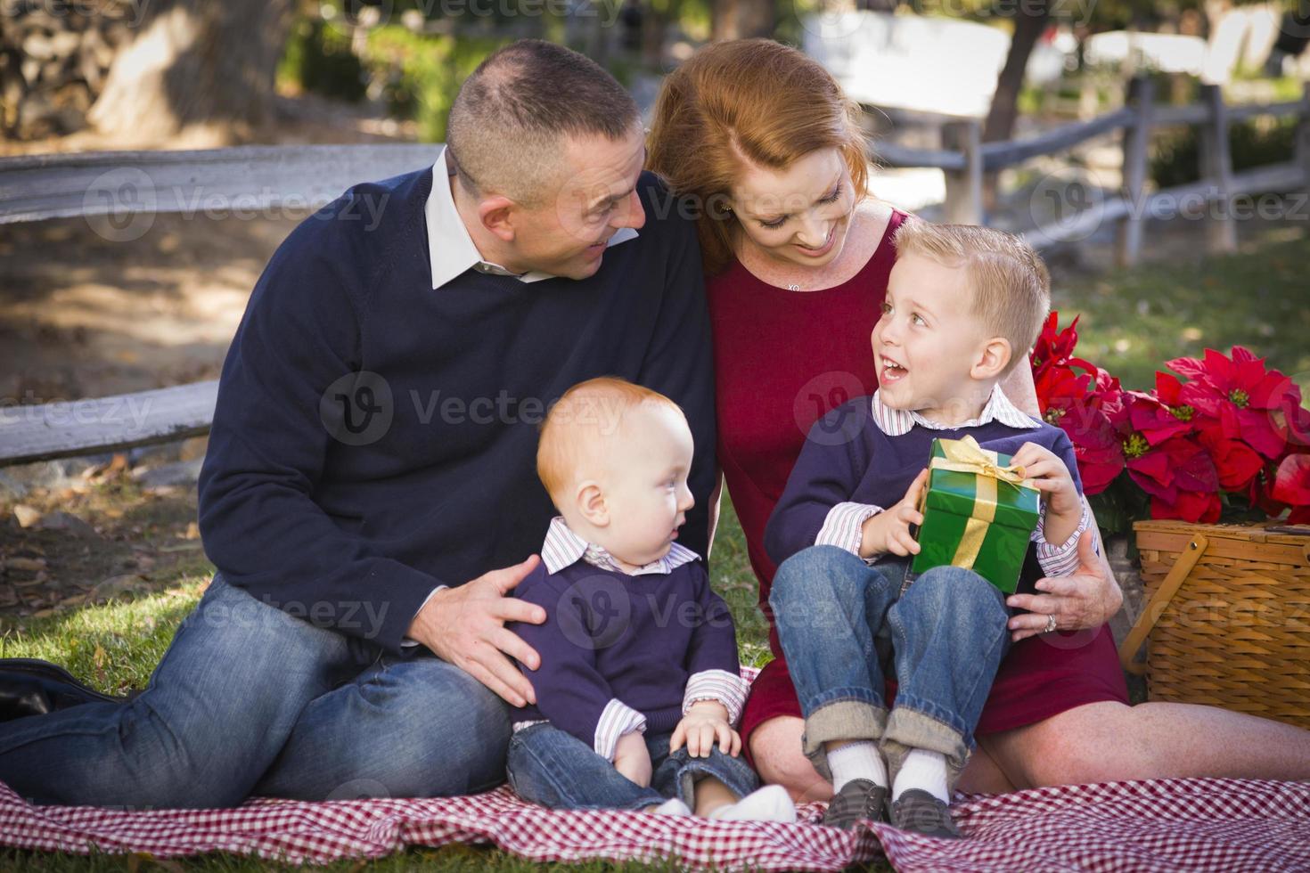 kleine junge familie, die weihnachtsgeschenke im park öffnet foto