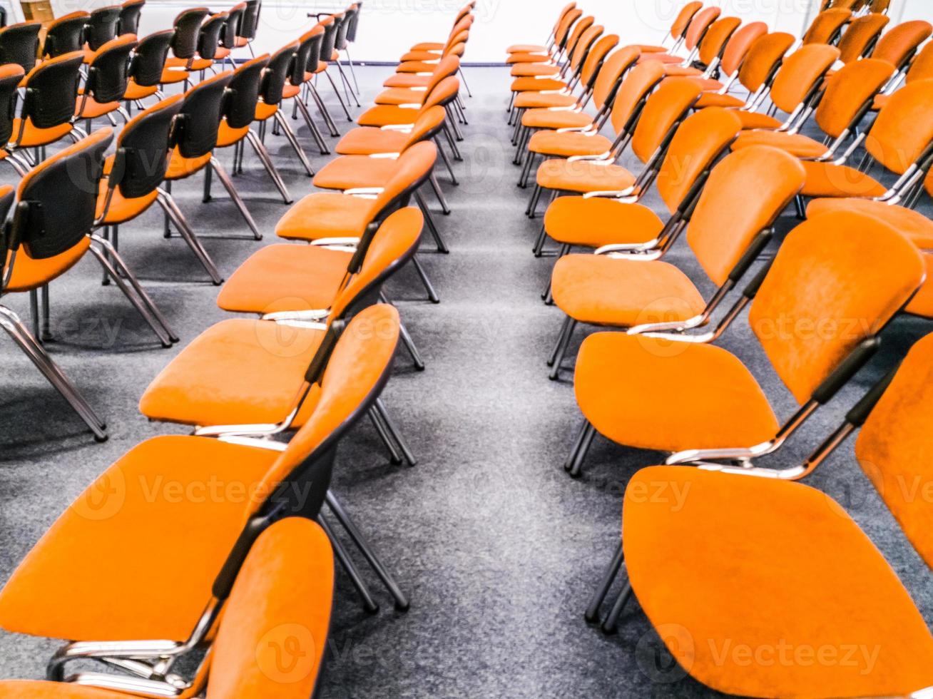 Innenraum des Besprechungsraums. Vorderansicht von Reihen von orangefarbenen Stühlen, die in einem Auditorium stehen. Sitzplätze in einem leeren Konferenzraum. Riesiger Halleninnenraum mit Teppich und Lichtern als Konferenzsaal im Luxushotel. foto