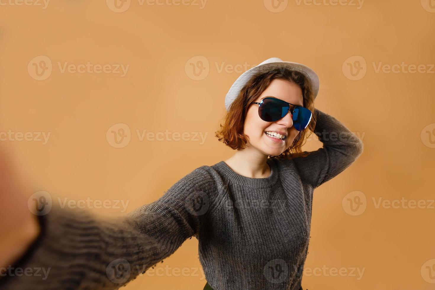 selbstporträt einer netten, erstaunlichen, hübschen, positiven, sexy frau, die selfie in zwei händen auf der frontkamera schießt, ihrem freund einen luftkuss zubläst, ein gepunktetes outfit hat, isoliert auf gelbem hintergrund foto