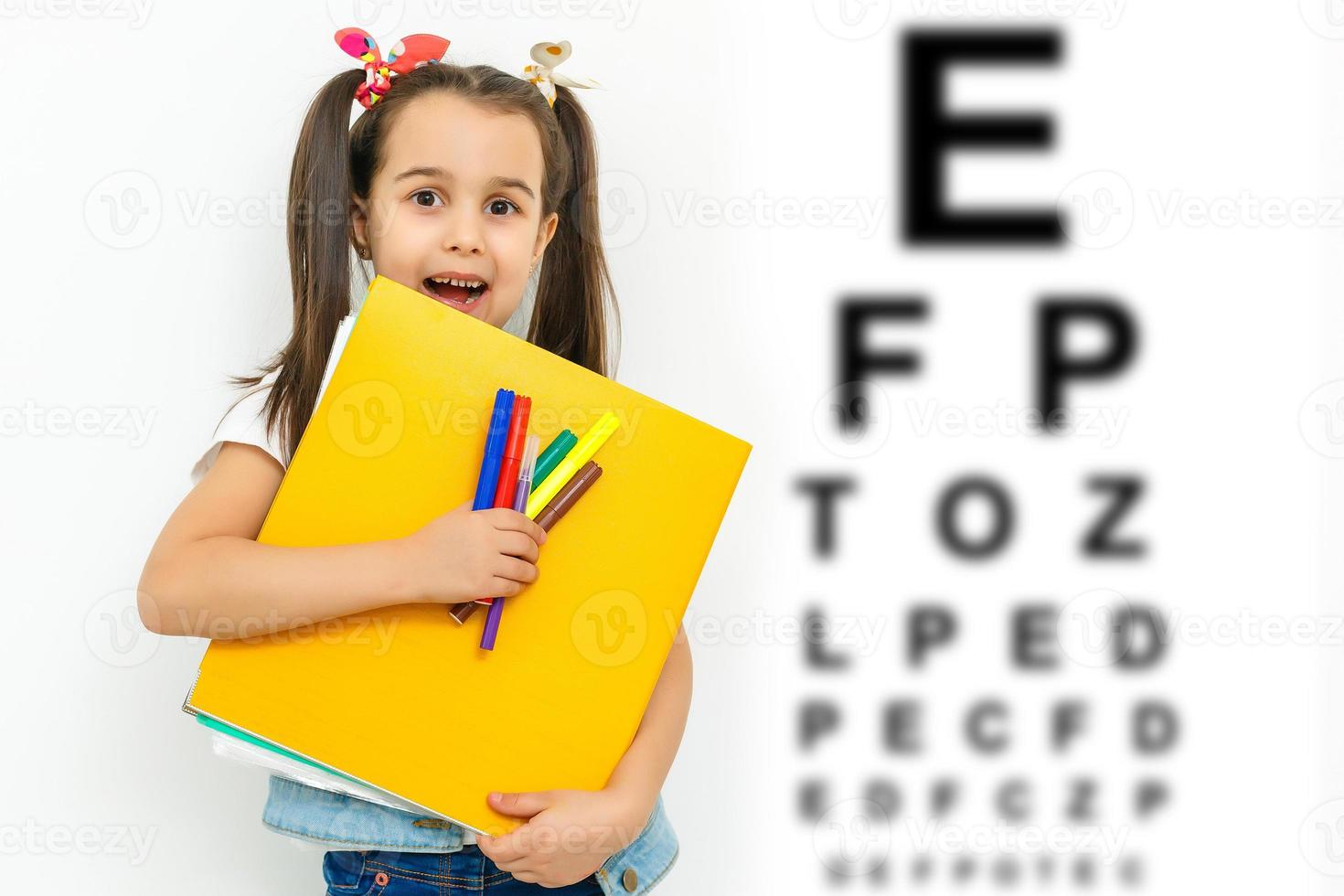 Kind beim Sehtest. kleines Kind, das eine Brille im Optikergeschäft auswählt. Sehkraftmessung für Schulkinder. Brillen für Kinder. arzt, der augenkontrolle durchführt. Mädchen mit Brille am Buchstabendiagramm. foto