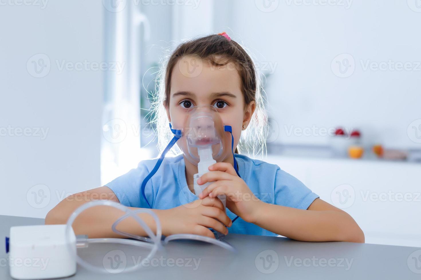 Das kleine kaukasische Mädchen atmet mit einer speziellen Maske, die hilft, einen Asthmaanfall zu stoppen oder die Symptome einer Atemwegserkrankung zu lindern. foto