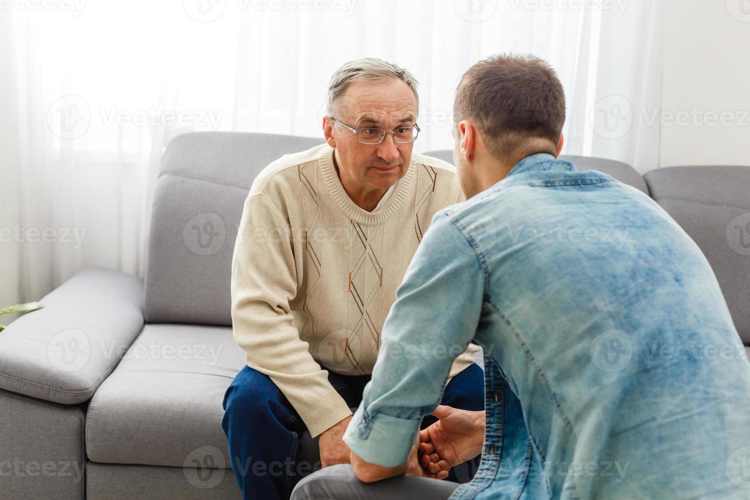 erwachsener sohn spricht zu hause mit depressivem vater foto