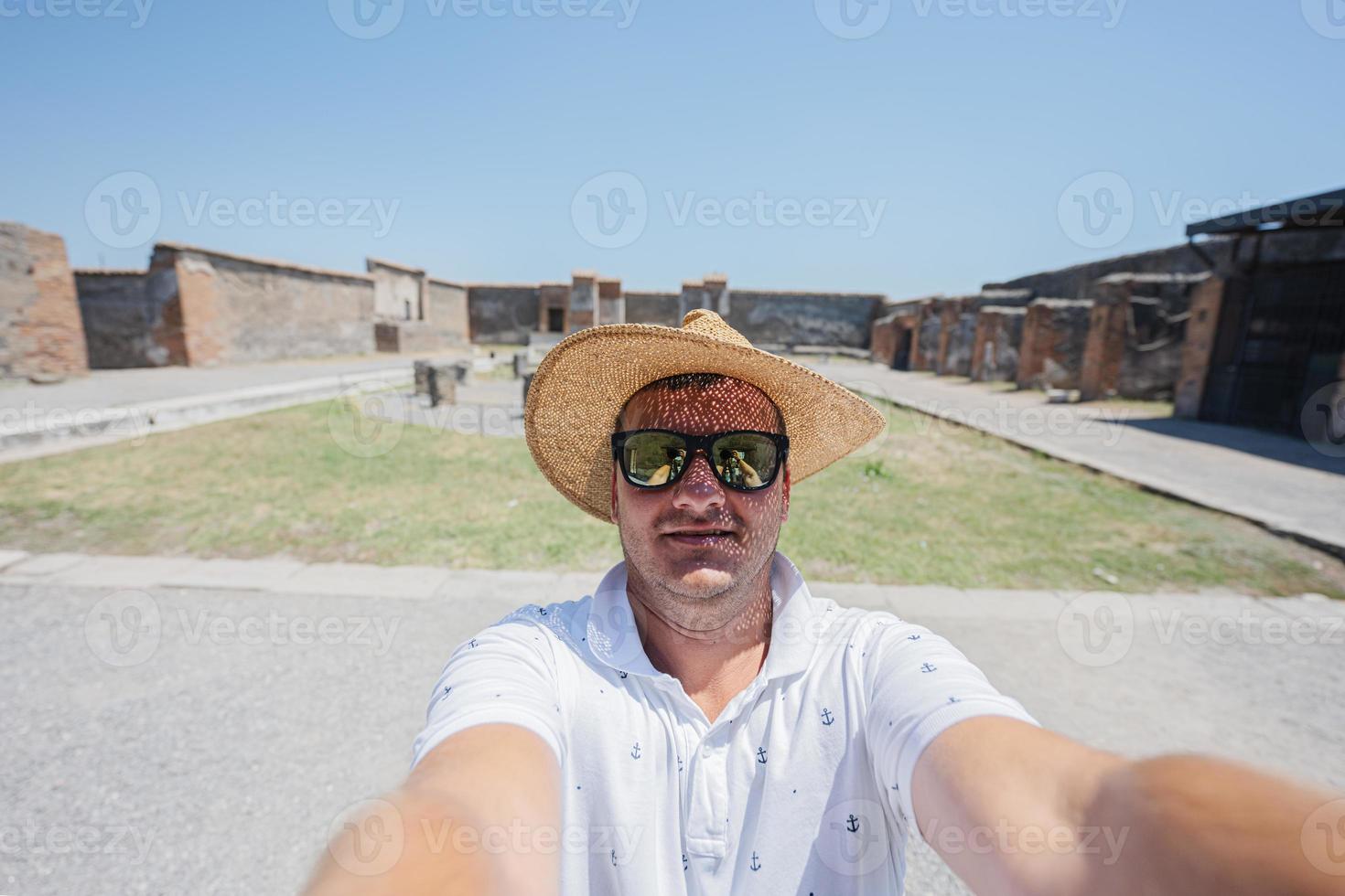 Mann Tourist in Hut und Sonnenbrille macht Selfie in der antiken Stadt Pompeji, Italien. foto