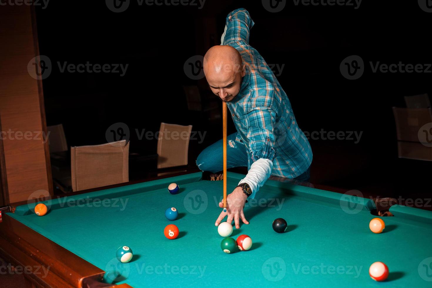 mann wählt einen schwierigen schlag auf poolbillard foto