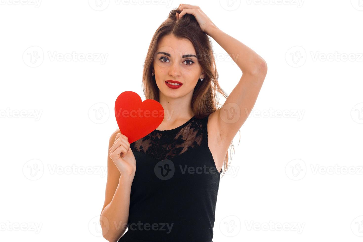 junge schöne brünette dame mit rotem herzen in den händen, die die kamera lokalisiert auf weißem hintergrund aufwerfen und betrachten. Valentinstag-Konzept. foto