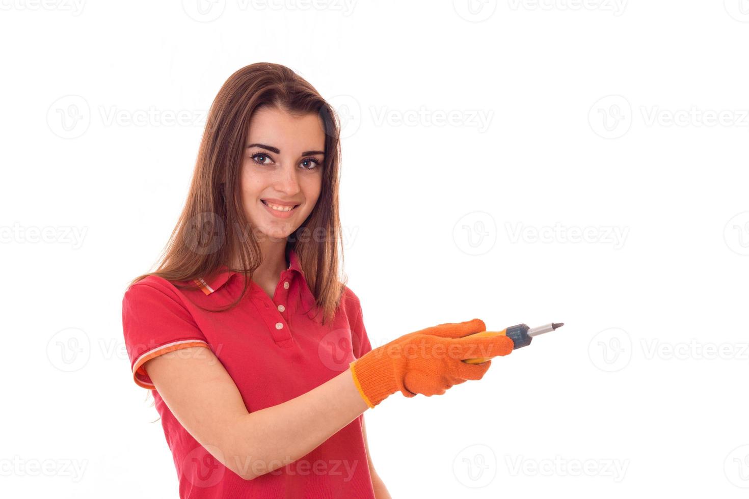 Porträt einer jungen attraktiven brünetten Gebäudefrau in roter Uniform mit Schraubendreher in den Händen macht Renovierung und lächelt vor der Kamera isoliert auf weißem Hintergrund foto