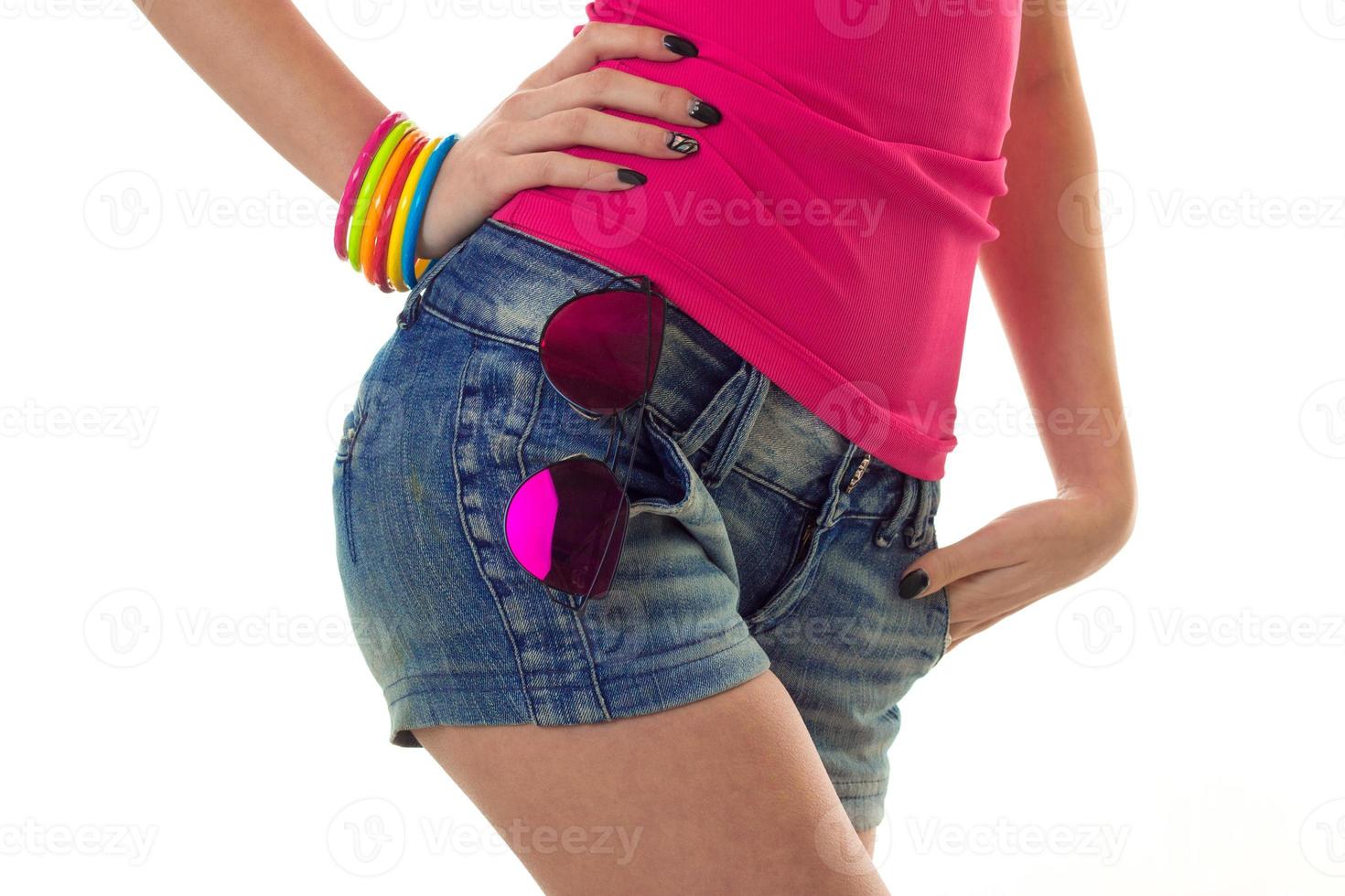 Nahaufnahme von weiblichen sexy Hüften in Jeans-Shorts mit Sonnenbrille isoliert auf weißem Hintergrund foto