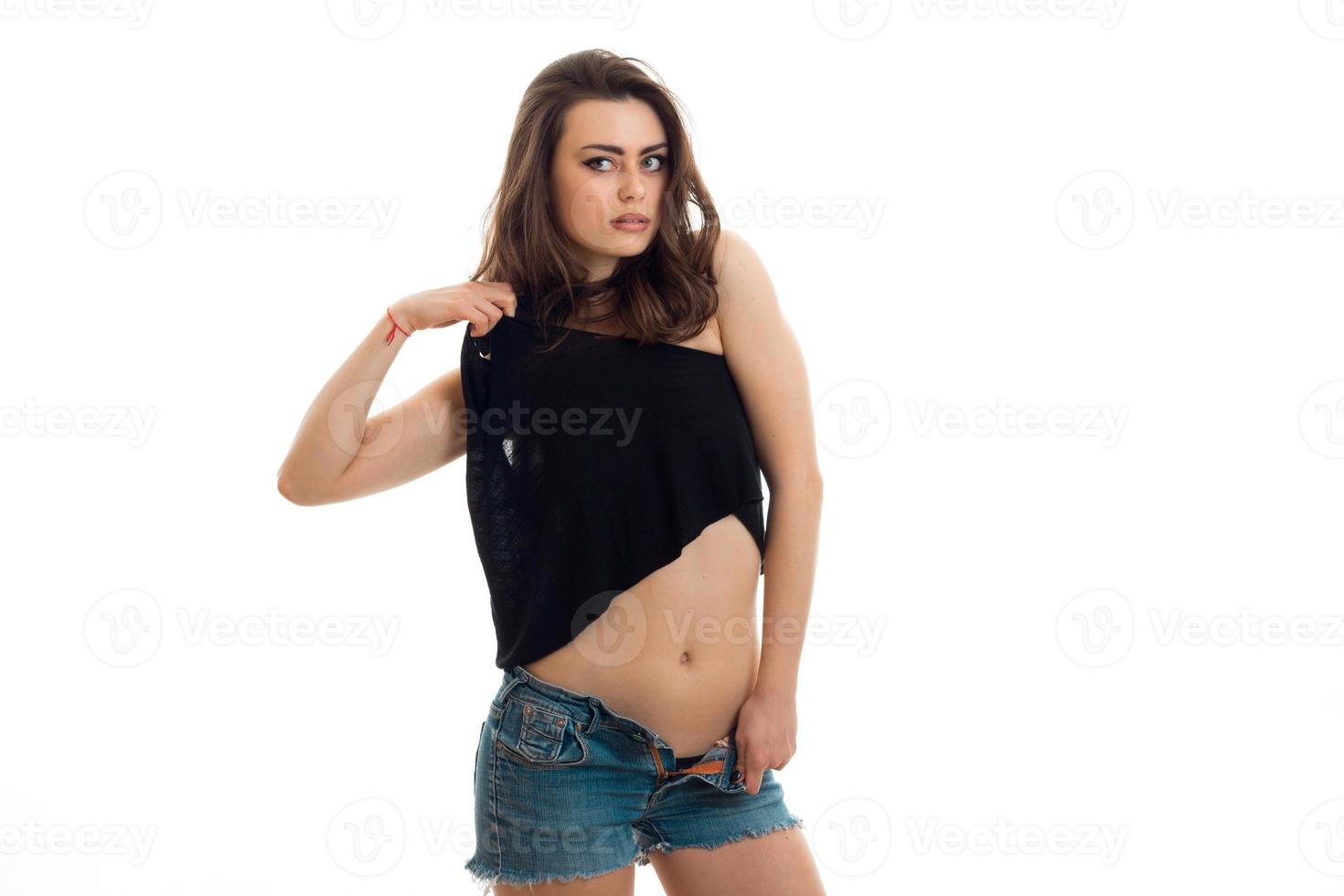 junge attraktive brünette schaut weg und posiert sexy für die kamera in jeansshorts und einem t-shirt foto