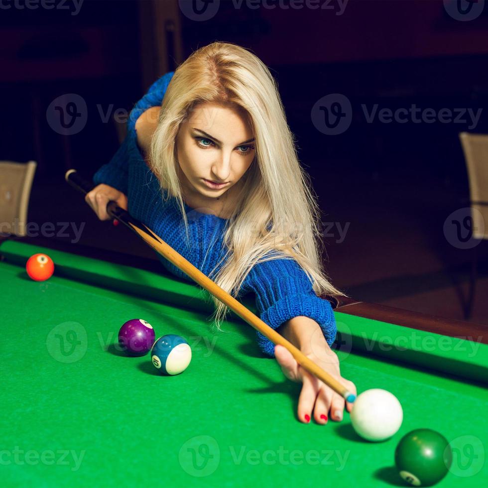 quadratisches Porträt einer ernsthaften jungen blonden Frau, die Billard spielt foto