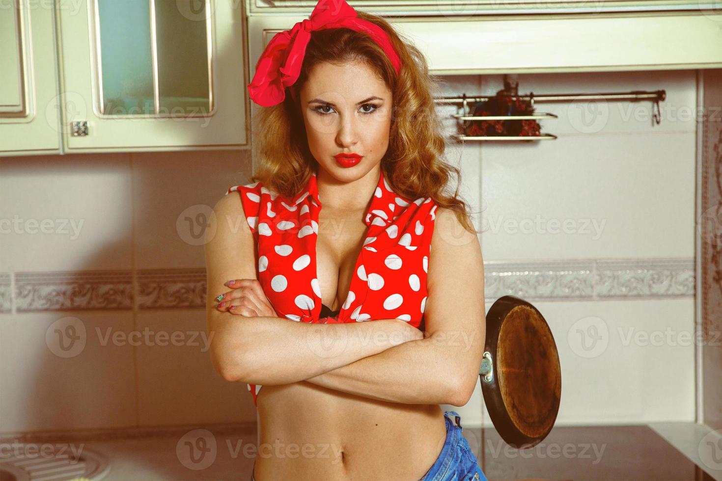 Horizontales Porträt einer sexy jungen Dame im Pinup-Stil, die mit einer Bratpfanne in der Küche posiert foto