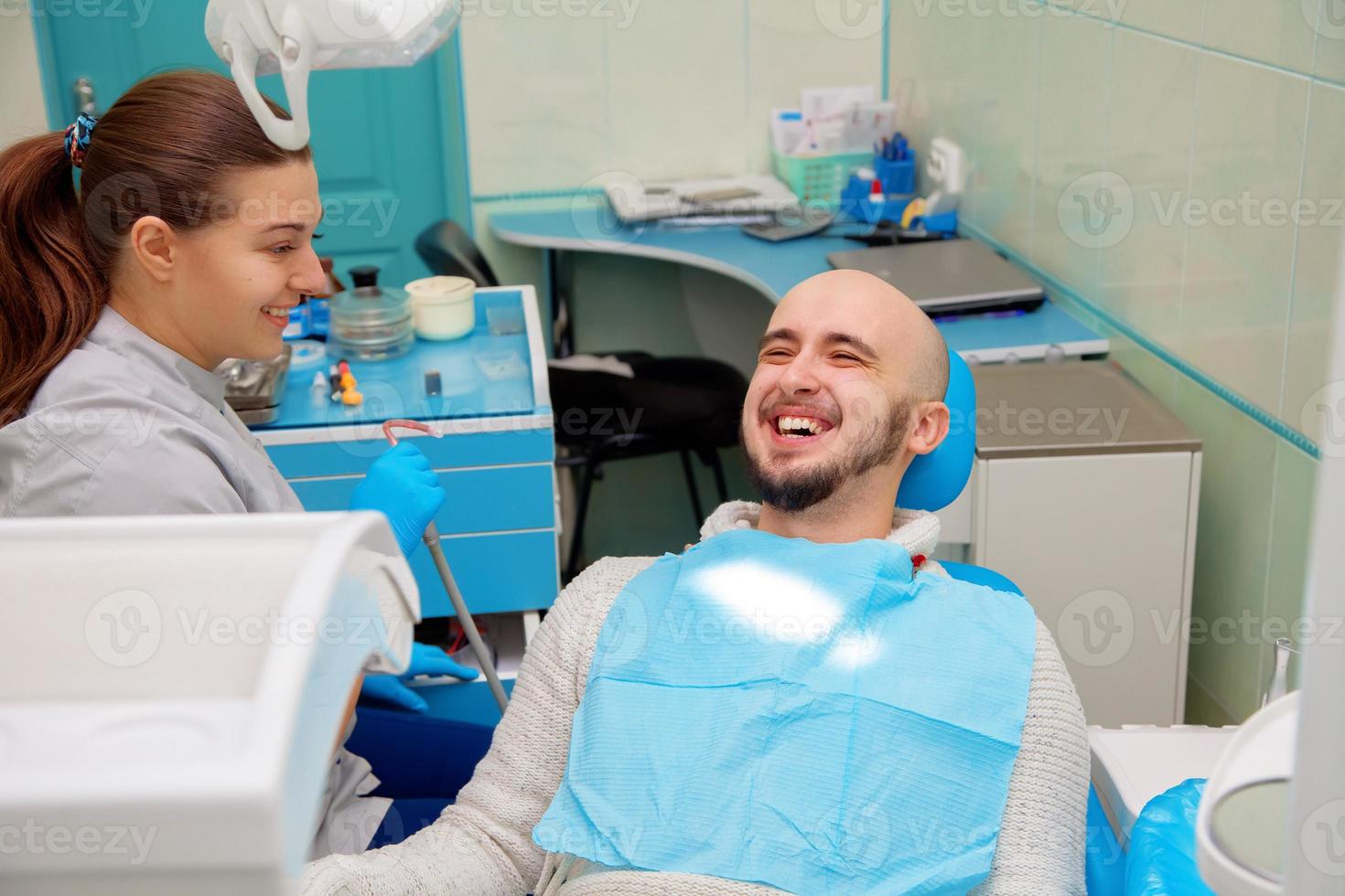 zahnarzt, der spaß mit dem patienten während der behandlung hat foto