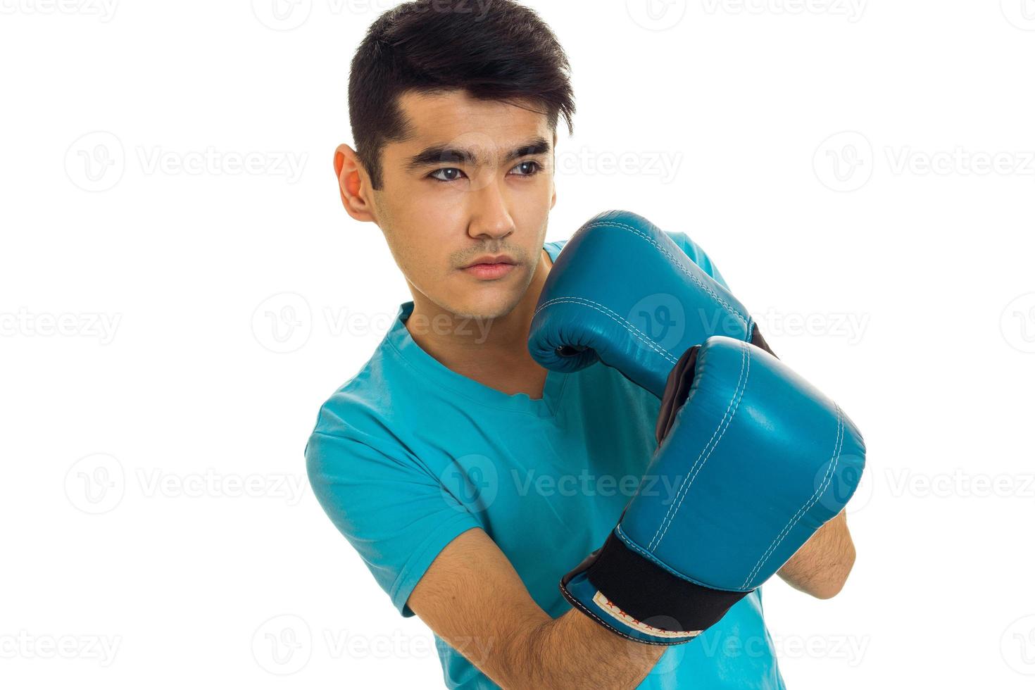 Porträt eines jungen starken Mannes im blauen Hemd, der Boxen in Handschuhen übt, isoliert auf weißem Hintergrund foto