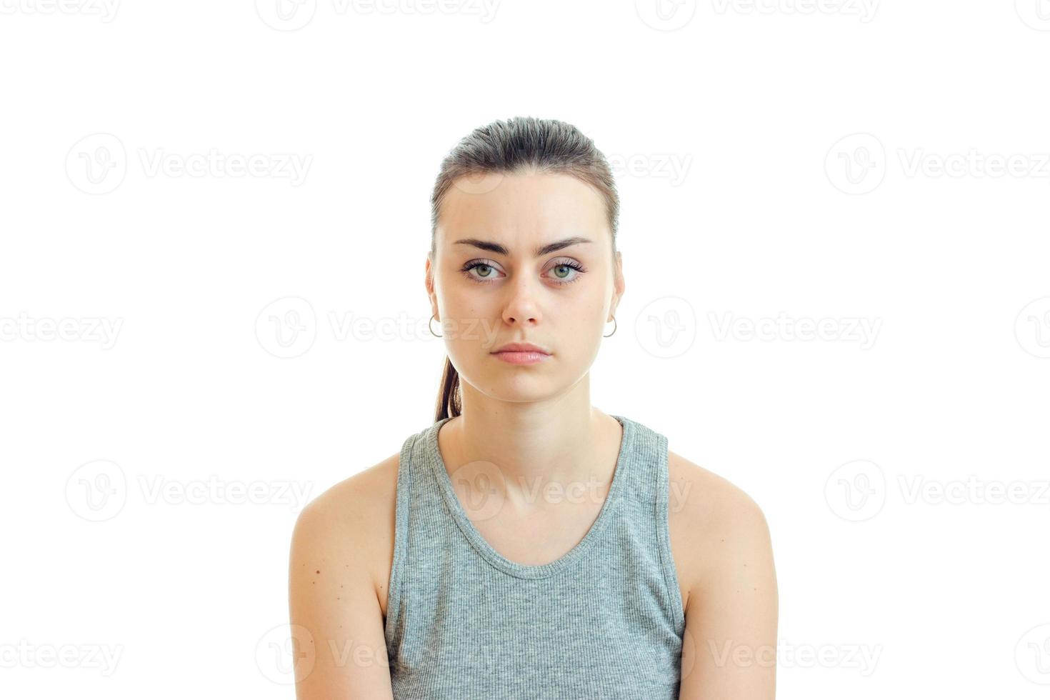 ernstes Porträt eines jungen Mädchens mit den gesammelten Haaren, das direkt in die Kamera schaut foto