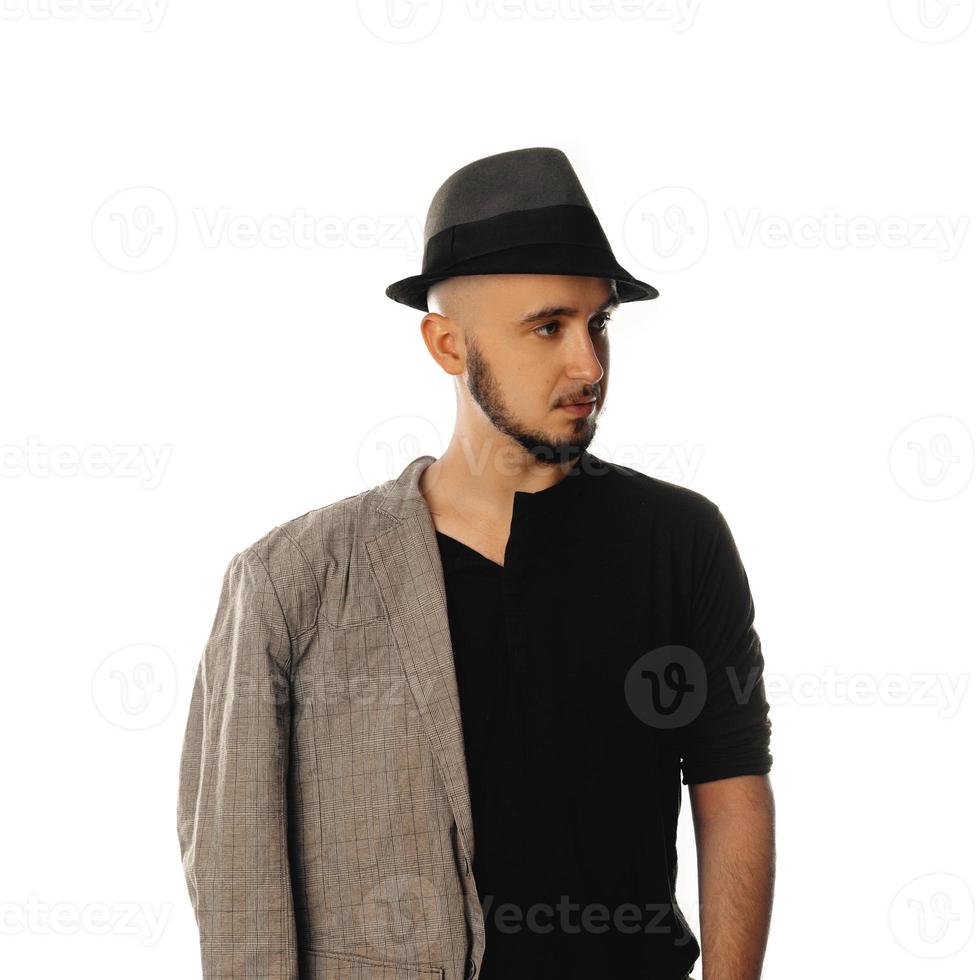 Ernsthafter junger unrasierter Mann mit Hut und Jacke, der wegschaut foto