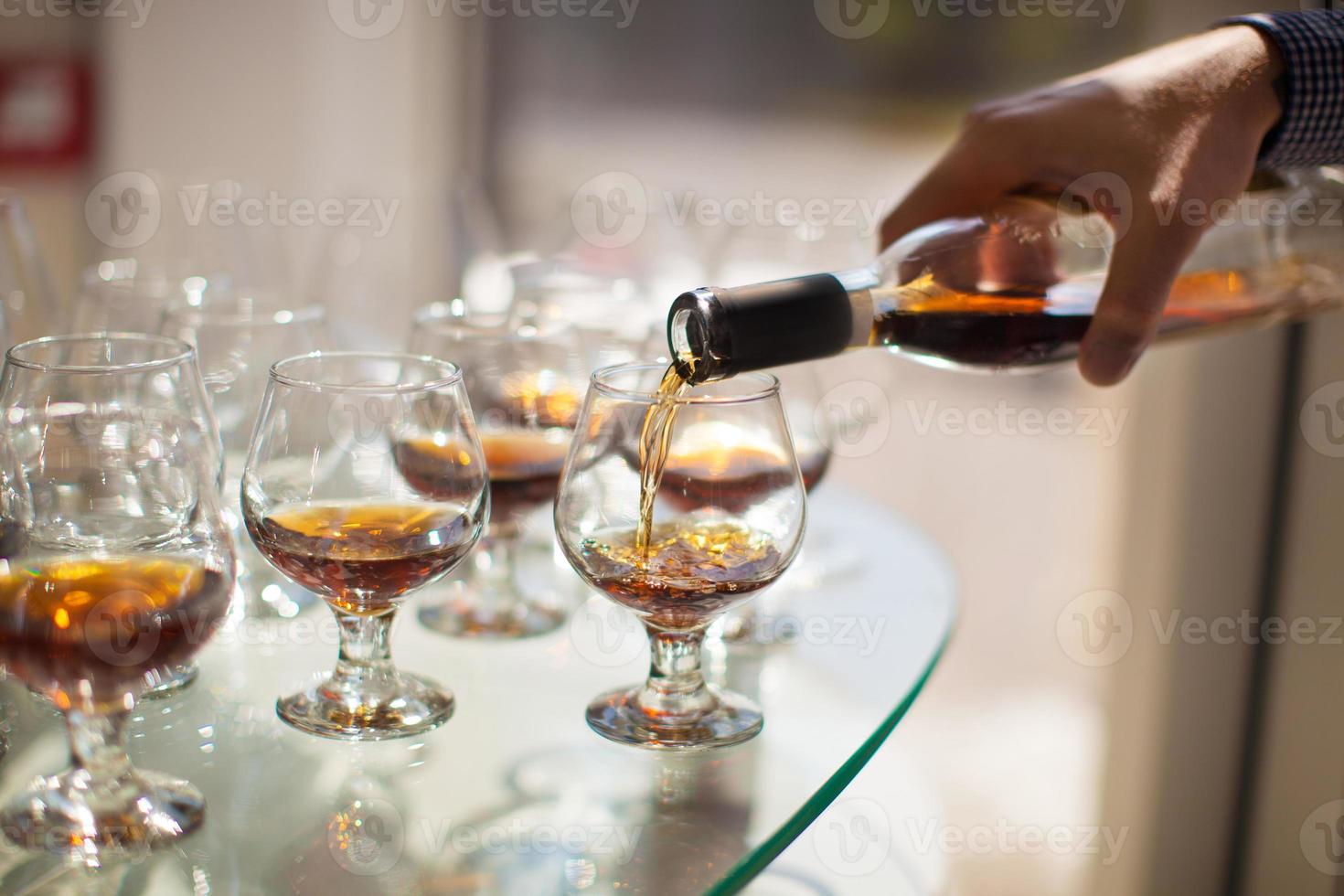 der kellner schenkt ein glas wein ein, cognac foto